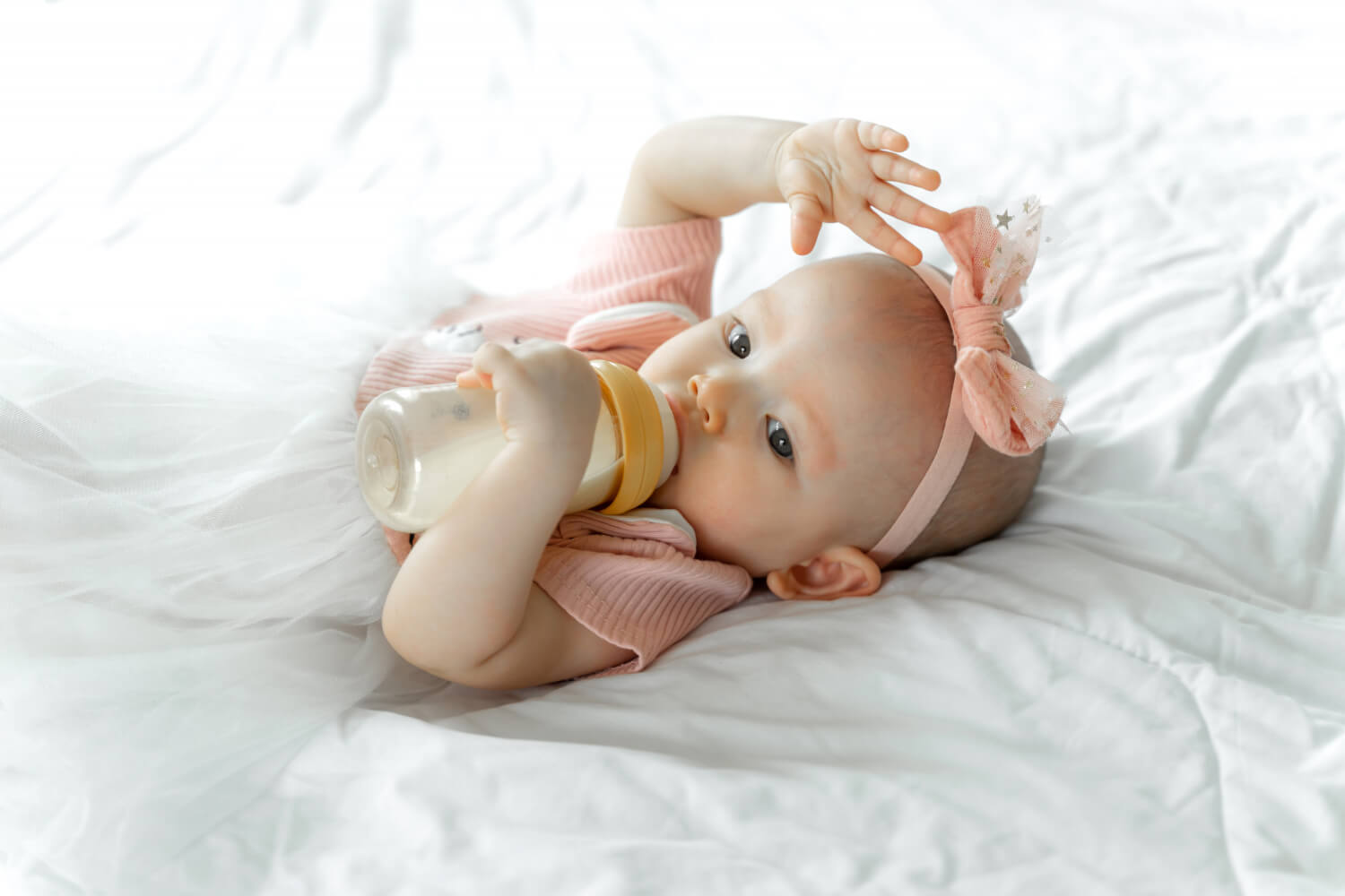 Adorable bébé tenant son biberon - Nutrition infantile optimisée pour la croissance. Découvrez les options de lait infantile adaptées aux besoins de votre tout-petit