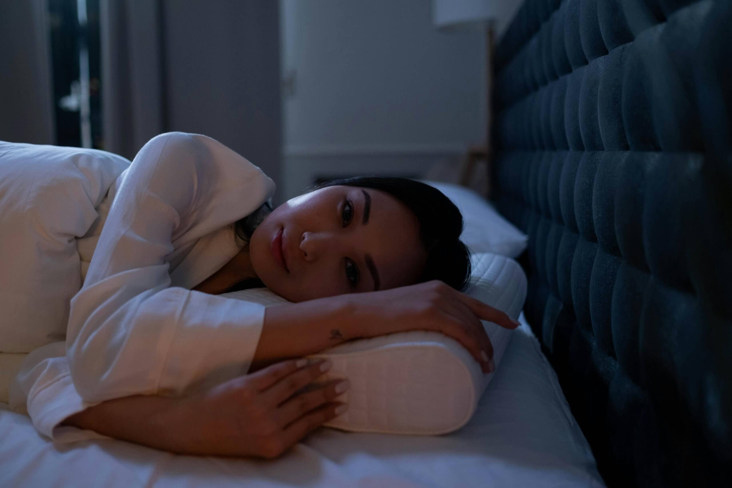 Femme allongée dans son lit, souffrant de troubles du sommeil à Ermont, illustrant le besoin d’un soutien naturel comme l’ostéopathie pour mieux dormir.