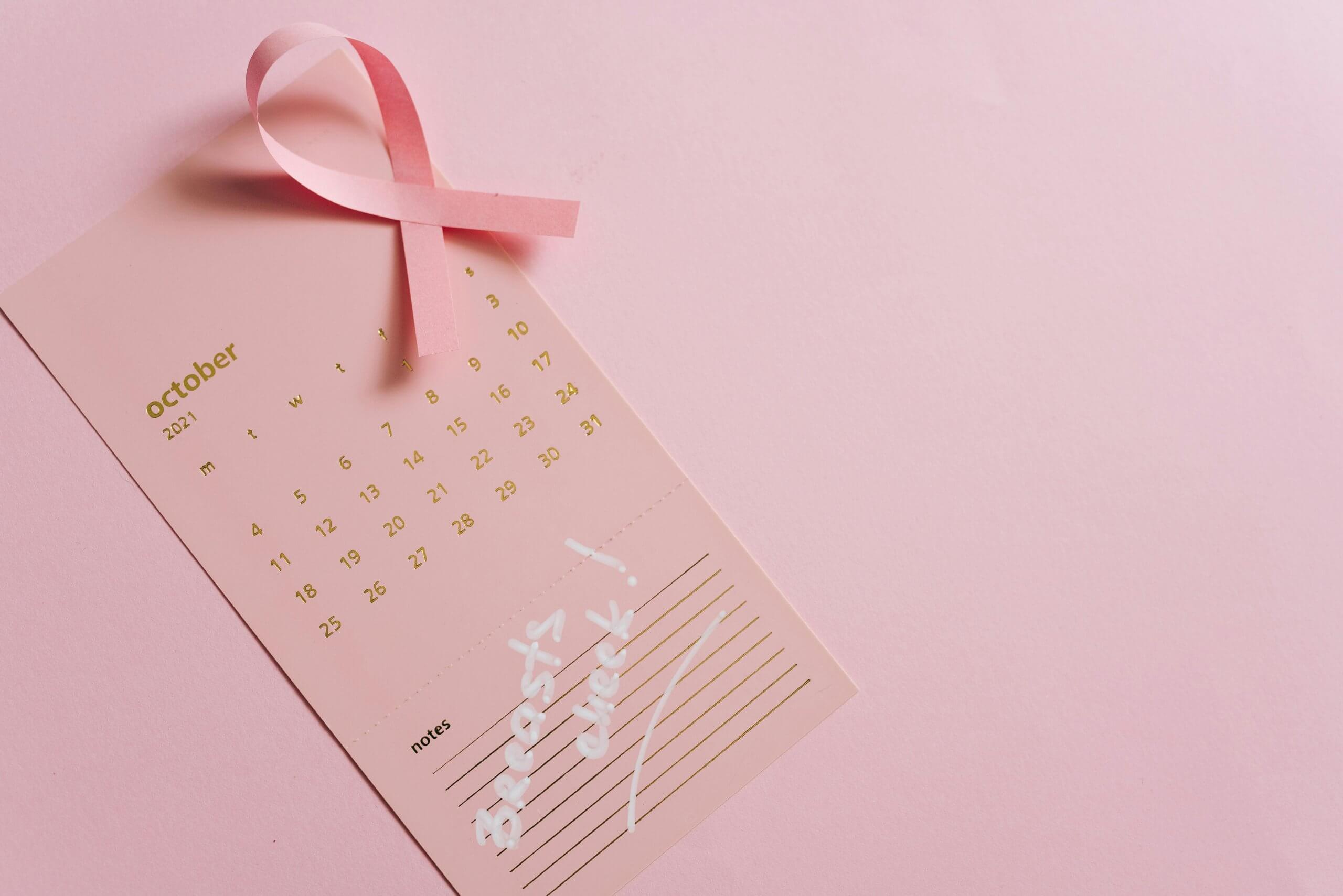 Ruban rose sur un calendrier d’octobre – symbole de la campagne Octobre Rose et de la prévention du cancer du sein, illustrant l’accompagnement en ostéopathie à Saint-Gratien pour les femmes pendant et après la maladie.