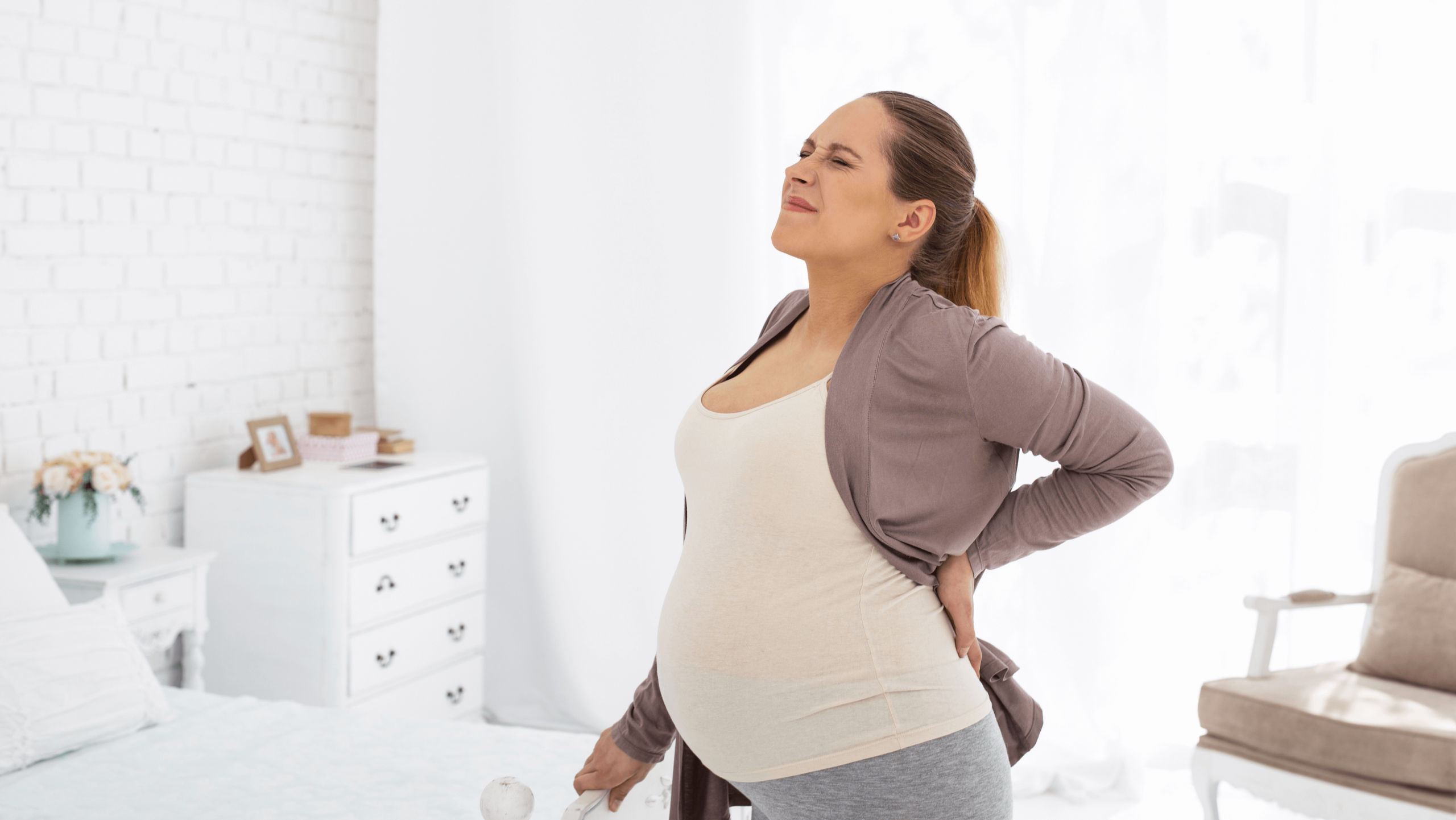 Femme enceinte tenant le bas de son dos, illustrant les douleurs lombaires fréquentes pendant la grossesse