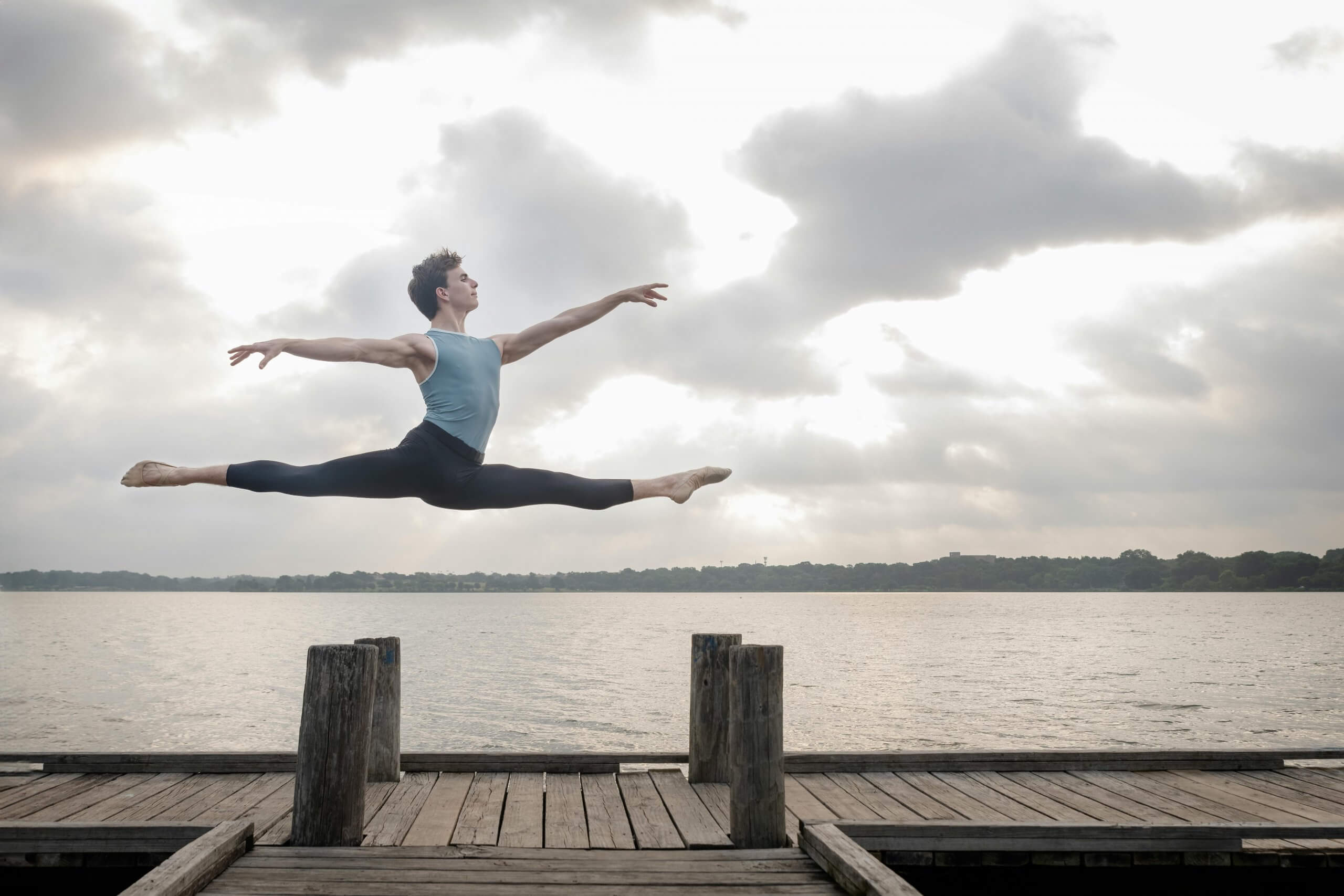 Un danseur en plein saut sur un ponton, illustrant la puissance de la concentration, du mental et de la maîtrise corporelle dans la performance sportive