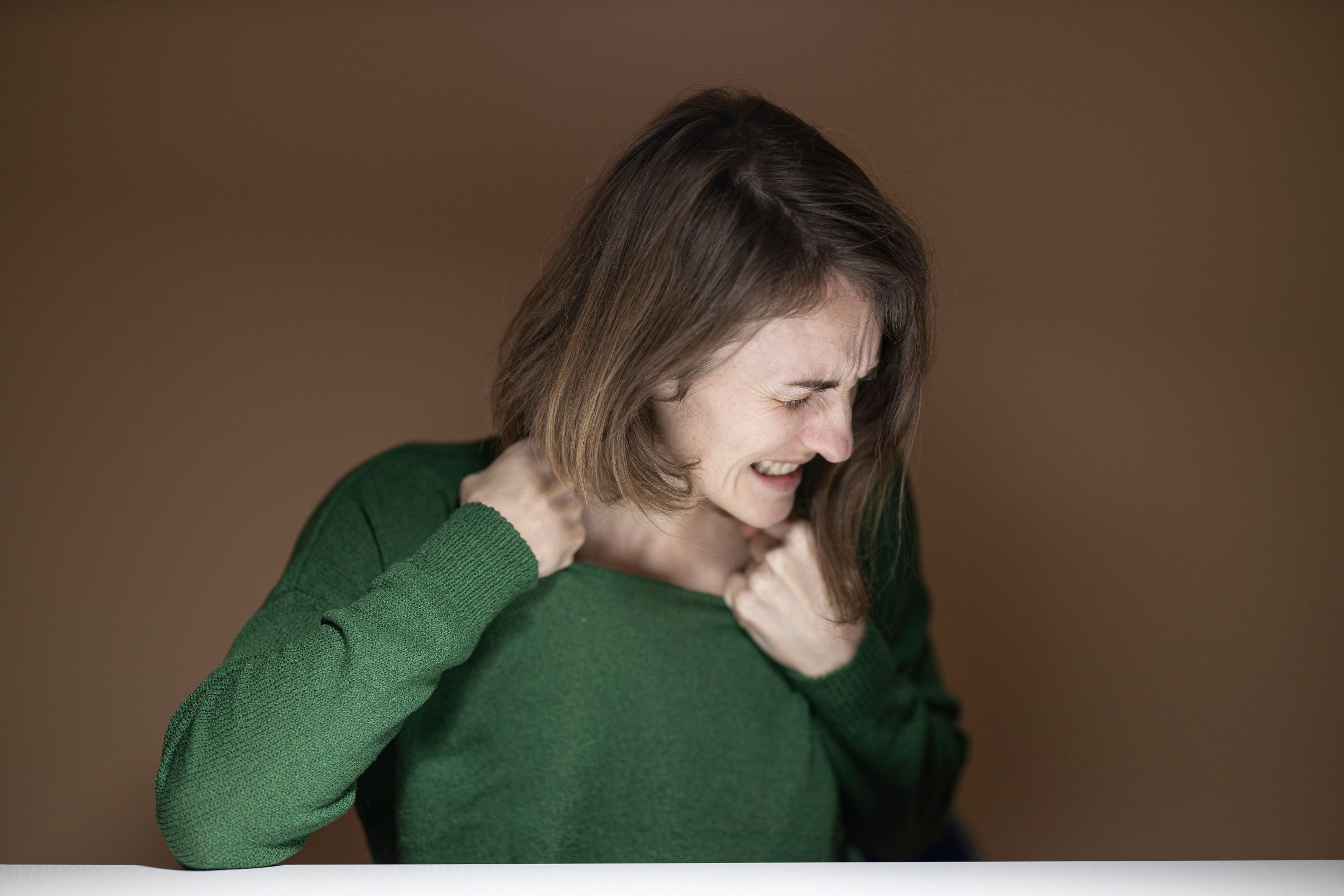 Femme souffrant de douleurs cervicales persistantes avec une sensation de tension dans la nuque et les épaules.