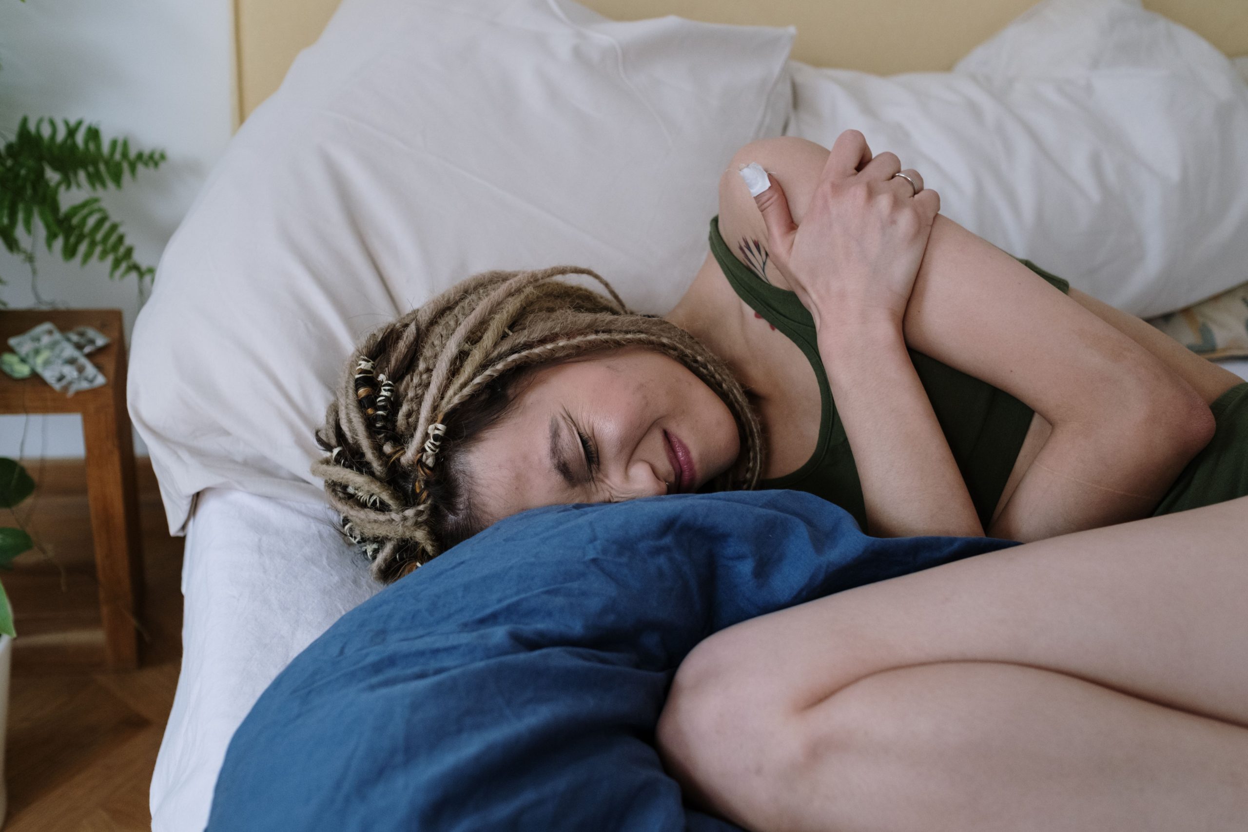 Femme allongée sur le côté dans son lit, souffrant d'une douleur à l'épaule pendant la nuit.